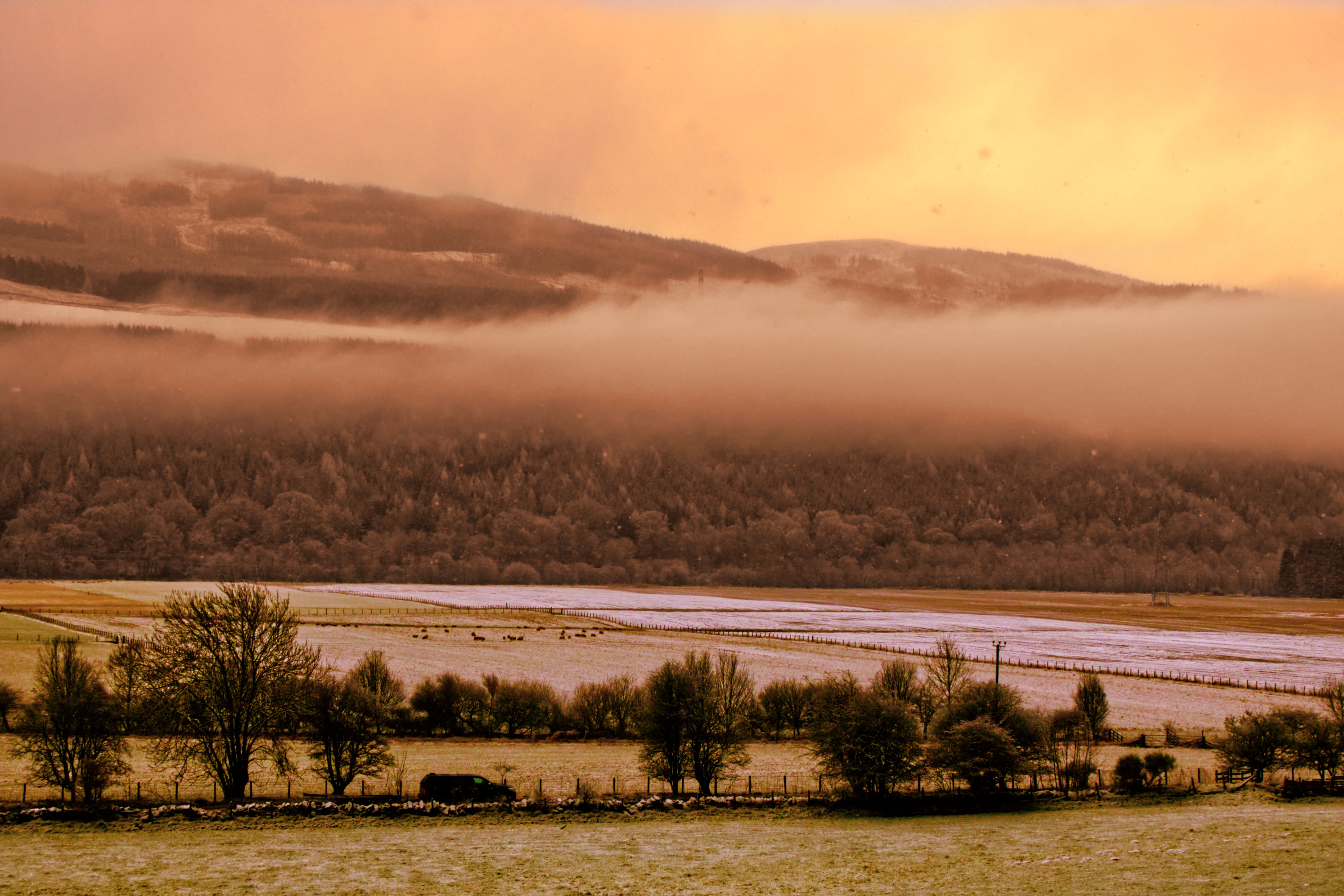 Copper light and mist drifting across a Highland valley